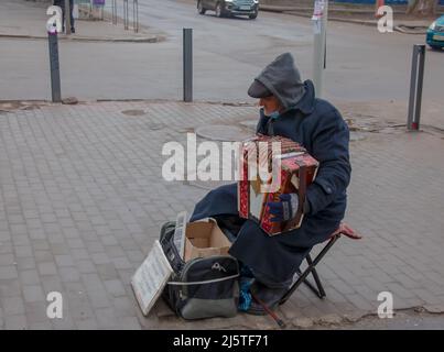 Dnepr, Ukraine - 02.10.2022: Un homme joue l'accordéon de bouton dans la rue en hiver. Banque D'Images