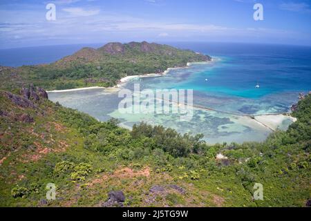 Vue aérienne d'une crique privée avec des eaux turquoise et des montagnes verdoyantes sur l'île de Curieuse, Seychelles. Banque D'Images