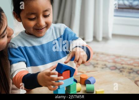 La mère et le fils d'Amérique latine enfant ayant des jeux amusants avec des blocs de jouets en bois à la maison - temps de famille ensemble Banque D'Images