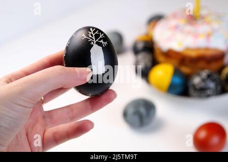 Effet de flou artistique sur l'œuf noir de Pâques avec décoration d'arbre. Macareux de Pâques. Gros plan œufs de Pâques pastel sur fond blanc. Fête de Pâques minimale Banque D'Images