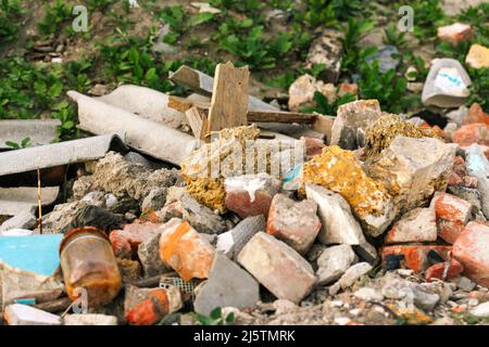 Recentrer d'énormes ruines, épave en Ukraine, la guerre. Maison après attaque russe. Grande pile de déchets sur fond d'herbe verte nature, réchauffement de la planète. Pollution. Banque D'Images