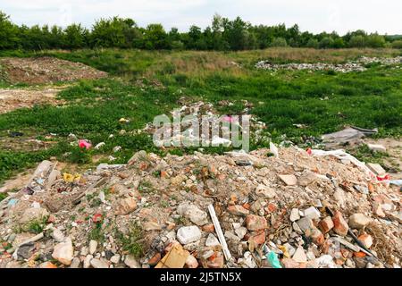 Recentrer d'énormes ruines, épave en Ukraine, la guerre. Maison après attaque russe. Grande pile de déchets sur fond d'herbe verte nature, réchauffement de la planète. Pollution. Banque D'Images