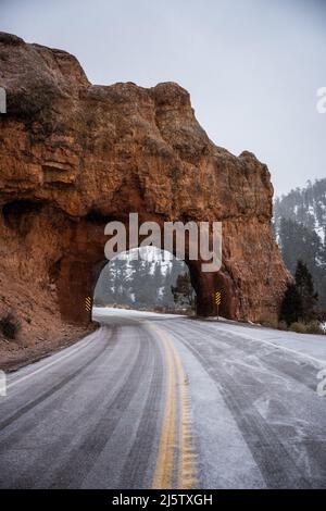 La route panoramique 12 couverte de neige traverse les tunnels en pierre rouge près de Bryce Canyon Banque D'Images