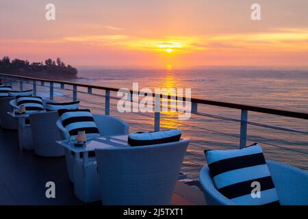 Taverne déserte avec tables et chaises sur le front de mer donnant sur la mer en soirée de printemps Banque D'Images