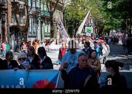 Porto, Portugal. 25th avril 2022. Les manifestants défilent avec des signes et des œillets rouges pendant la parade. Le défilé du 25th avril célèbre la Révolution de la nation qui a eu lieu en 1974. À Porto, les mouvements civils ont organisé un défilé en commençant devant la PIDE (police politique) maintenant éteinte et se terminant au coeur de la ville dans l'Avenida dos Aliados (avenue alliés). Crédit : SOPA Images Limited/Alamy Live News Banque D'Images