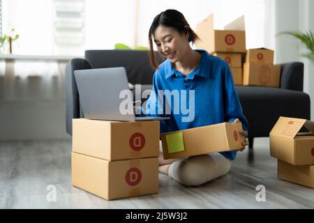 Expédition shopping en ligne, démarrage propriétaire de petite entreprise écrivant l'adresse sur boîte de carton au lieu de travail. Femme asiatique freelance petite entreprise Banque D'Images