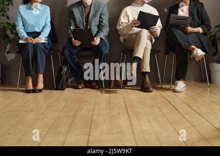 Gros plan des personnes assises sur des chaises et remplissant des formulaires dans le couloir des bureaux Banque D'Images