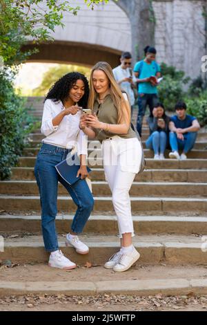 Deux jeunes étudiantes multiraciales regardant un carnet dans un escalier Banque D'Images