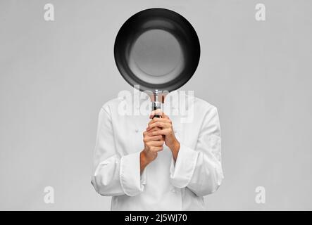 femme chef couvrant son visage avec une poêle à frire Banque D'Images