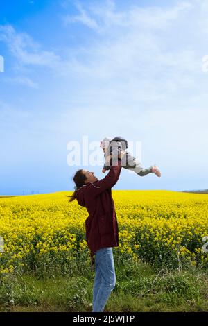 Une femme tenant son bébé dans un champ lors d'une belle journée ensoleillée Banque D'Images