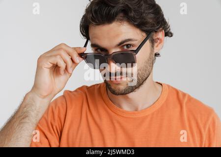 Jeune femme brune portant des lunettes de soleil regardant la caméra isolée sur fond blanc Banque D'Images
