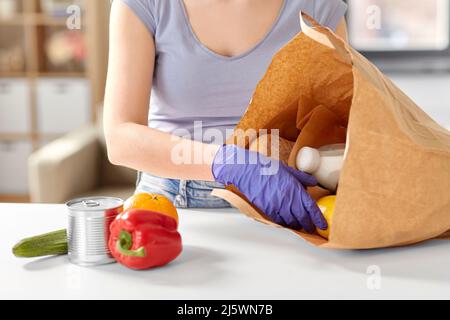 femme en gants prenant des aliments dans un sac en papier à la maison Banque D'Images