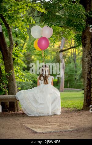 Fille habillée en communion dans un parc entouré par la nature et la couleur Banque D'Images