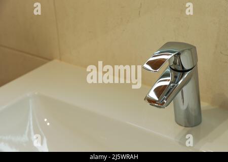 Robinet de salle de bain. Robinet chromé dans une salle de bain moderne avec lavabo blanc, espace pour du texte. Robinet de salle de bain Banque D'Images