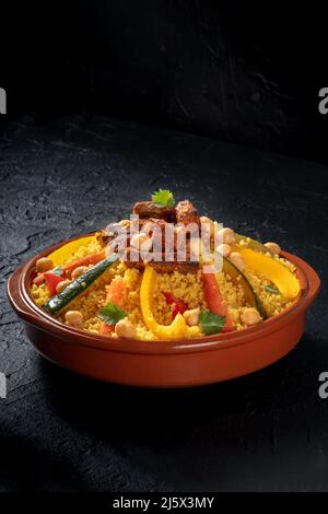 Couscous à la viande et aux légumes, cuisine arabe traditionnelle, sur fond d'ardoise noire Banque D'Images