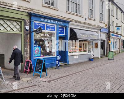 Homme marchant dans une ruelle à côté de la boutique d'informations Blue Painted Marketplace à Kendal, la plus grande ville de la région des lacs sud d'Angleterre Banque D'Images