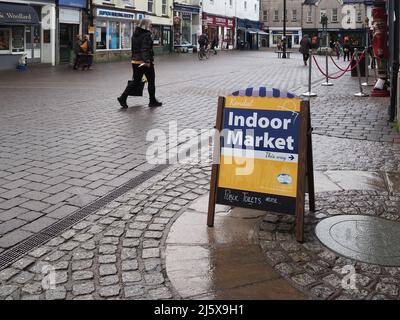 Signe faisant la promotion du marché intérieur avec une personne qui le passe, probablement en ignorant les plus petites boutiques pour les plus grands magasins à Kendal, Cumbria, Royaume-Uni Banque D'Images