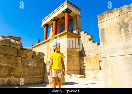 Une petite fille s'arrête pour prendre une photo d'œuvres d'art sur les murs du palais minoen à Knossos. Crète, Grèce Banque D'Images