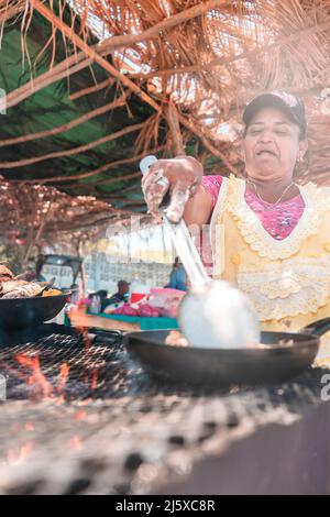 Photo verticale d'une femme latine âgée qui prépare du poisson frit sur la plage de Masachapa, au Nicaragua. Concept des métiers, du travail et de l'activité des personnes âgées Banque D'Images