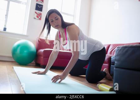 Femme enceinte s'exerçant sur un tapis de yoga à la maison Banque D'Images