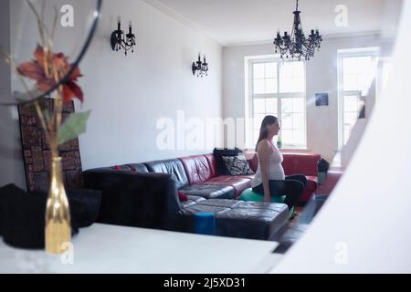 Femme enceinte s'entraîner sur un ballon de fitness à la maison Banque D'Images