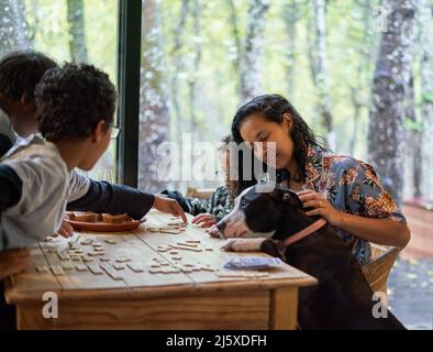 Famille avec un chien jouant au scrabble à la table à manger Banque D'Images