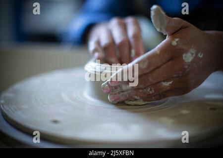 Gros plan des mains de la femme utilisant la roue de poterie Banque D'Images