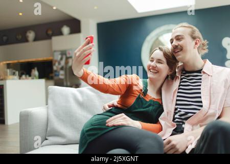 Un jeune couple heureux prend le selfie sur le canapé du salon Banque D'Images
