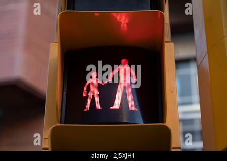 Un feu rouge, indiquant un arrêt, une prudence, à un passage de côté dans une zone scolaire, montre une figurine d'un enfant et d'un adulte tenant les mains Banque D'Images