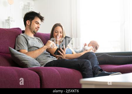 mère et père avec leur nouveau-né sur le canapé avec une tablette numérique Banque D'Images