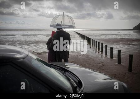 Couple sous un parapluie sur une plage d'hiver humide Banque D'Images