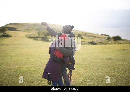 Couple de randonneurs affectueux prenant le selfie dans l'herbe ensoleillée Banque D'Images