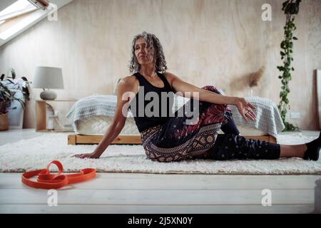 Femme de haut niveau pratiquant le yoga sur le plancher de la chambre Banque D'Images
