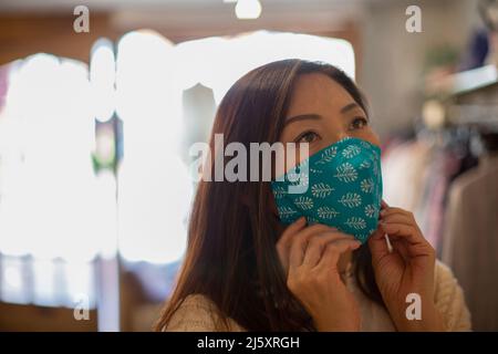 Femme portant un masque facial en magasin Banque D'Images
