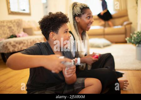 Mère et fils enthousiastes jouant à un jeu vidéo au sol du salon Banque D'Images