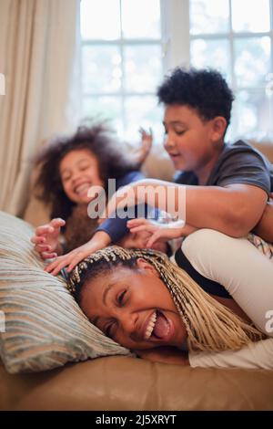 Mère et enfants joueurs sur le canapé Banque D'Images
