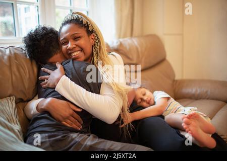 Une mère heureuse embrasse son fils sur le canapé du salon Banque D'Images