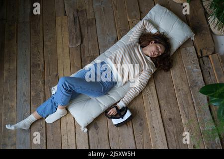 Femme millénaire détendue rêvant après avoir utilisé l'interface de réalité virtuelle, vue de dessus Banque D'Images