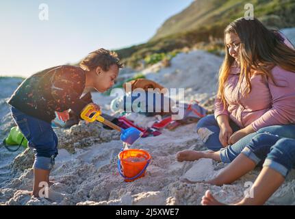 Mignon garçon jouant dans le sable avec une pelle et un seau sur la plage Banque D'Images