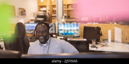 Homme d'affaires souriant avec micro-casque au bureau Banque D'Images