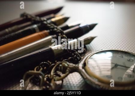 Vieille montre de poche avec des stylos à l'ancienne, concept- littérature Banque D'Images