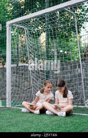 deux jeunes filles de charme dans des vêtements identiques avec des smartphones à l'extérieur. les enfants surfent sur le net. addiction de smartphone. les enfants dans les réseaux sociaux. textinin Banque D'Images