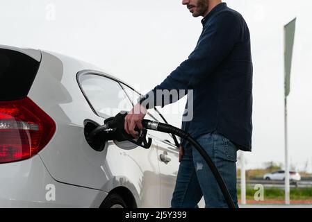 Un homme écourté méconnu remplit le réservoir de véhicule à la station-service pendant la crise énergétique Banque D'Images