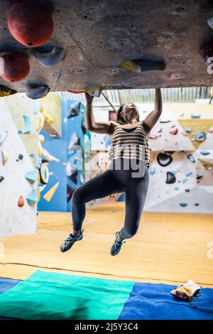 Femme grimpeur suspendu au mur d'escalade Banque D'Images