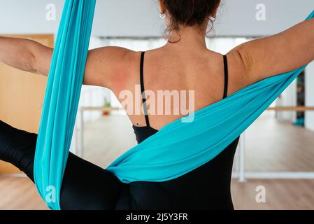 Courte femme pieds nus active non reconnaissable en forme d'oreille active noire pratiquant la posture Utthita Hasta Padangusthasana sur le hamac pendant le train de yoga aérien Banque D'Images