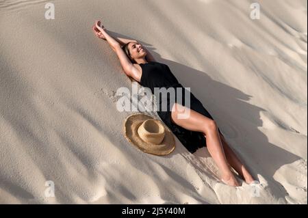 Jeune touriste femelle couché sur une colline de sable tout en explorant les dunes de Corralejo au coucher du soleil dans Fuerteventura îles Canaries Espagne Banque D'Images