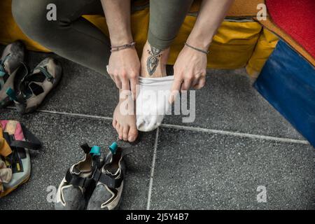 Femme grimpeur rock qui pose des chaussettes et des chaussures Banque D'Images