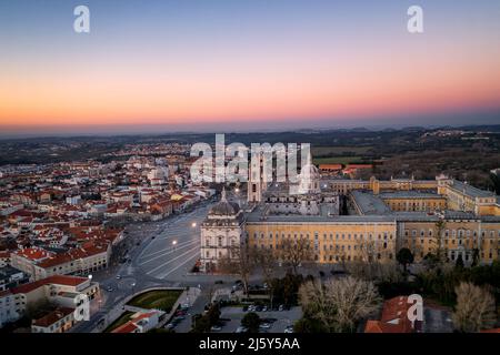 Vue aérienne pittoresque de l'ancienne ville de Mafra avec des bâtiments résidentiels et des routes sous un ciel sans nuages au coucher du soleil au Portugal Banque D'Images