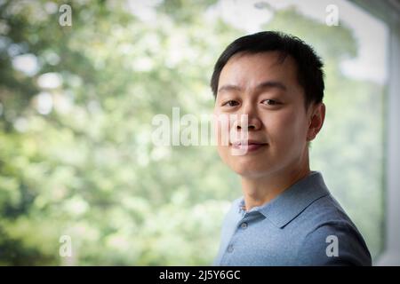 Portrait confiant, homme souriant à la fenêtre Banque D'Images