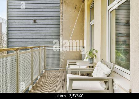 Chaises placées près d'une table avec plantes en pot et clôture en métal sur le balcon donnant sur les bâtiments situés dans la ville le jour d'été Banque D'Images